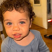 Cohen joined the competition — help win amazing prizes! child, toddler, curly_hair, blue_eyes, blue_shirt, indoor, floor, door, fan, expression, face, person, young_child, messy_shirt, hair, skin, mouth, eyes, standing, room