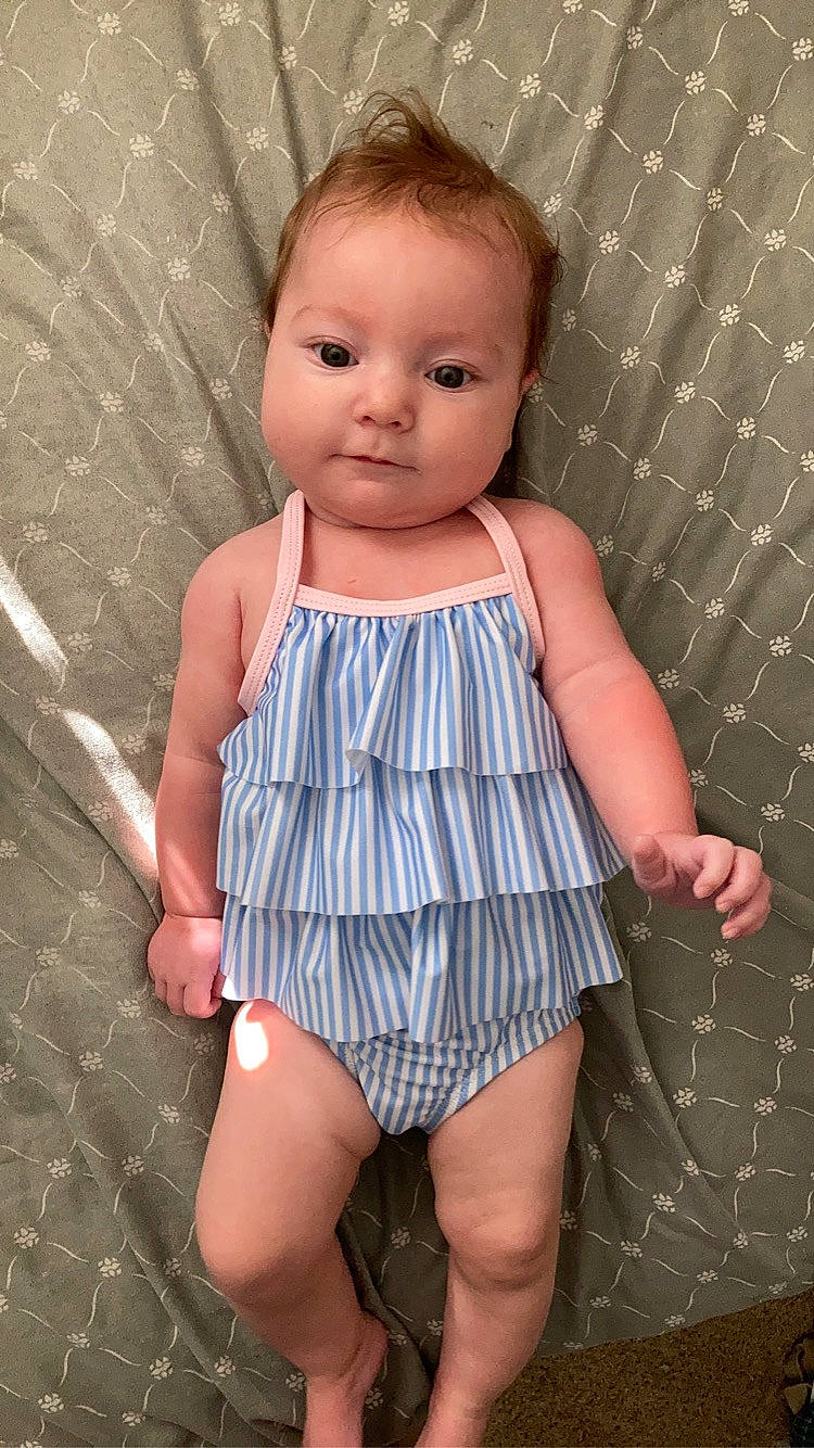 Alaia is registered to the contest to win money with this photo: baby, baby_toddler_clothing, day_dress, dress, eye, face, finger, hair, head, human_leg, iris, nail, one_piece_garment, pattern, person, pink, skin, sleeve, thigh, toddler