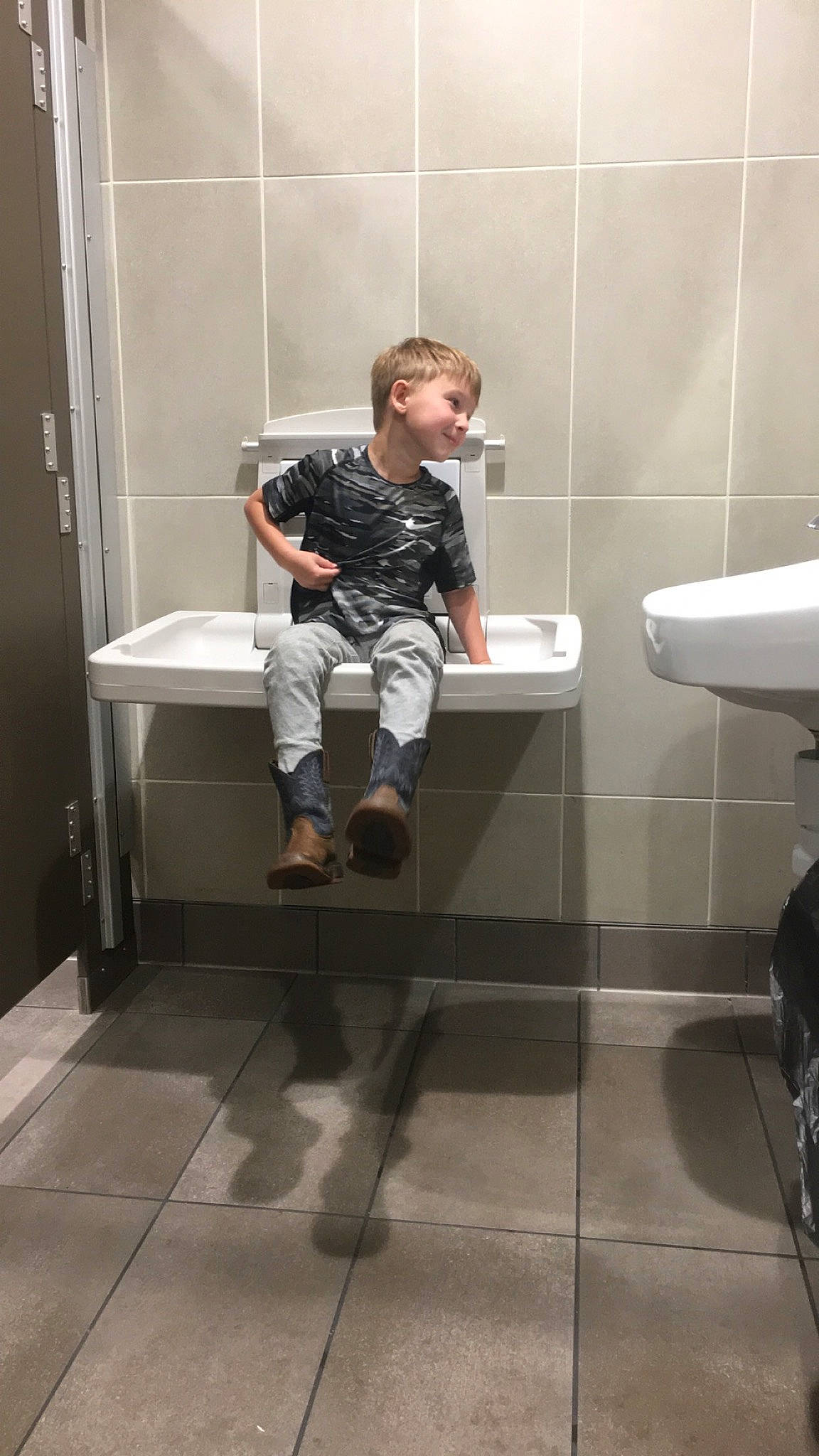 Braxtyn is registered to the contest to win money with this photo: bathroom, cleanliness, composite_material, door, floor, flooring, fun, household_supply, human_leg, joy, knee, paper, paper_product, person, plumbing, plumbing_fixture, reflection, room, sink, sitting