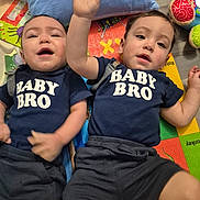 Aaron is registered to the contest to win money with this photo: baby, brother, toddler, child, matching_clothing, navy_shirt, play_mat, toy, pillow, smiling, lying_down, indoor, cute, infant, sibling, shorts, happy, face, person, casual