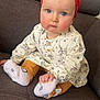 baby, child, infant, sitting, couch, red_headband, blue_eyes, white_dress, patterned_clothing, orange_pants, white_socks, hand, face, cute, indoors, furniture, portrait, expression, small_child, young