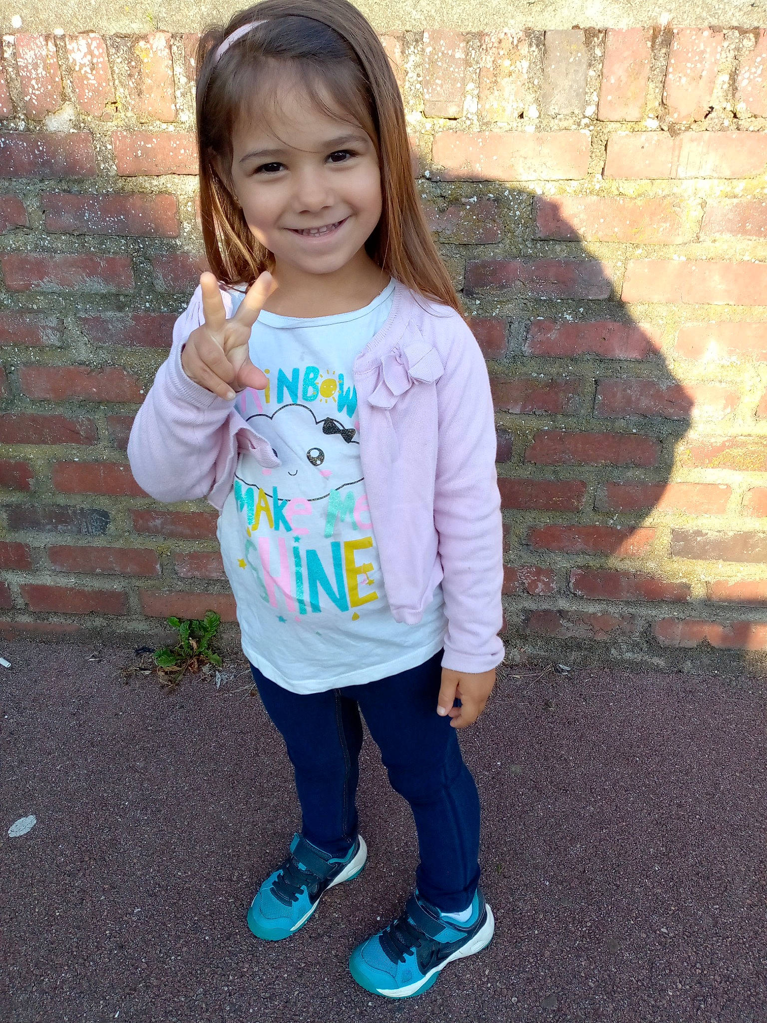 Gína participe au concours pour gagner de l'argent avec cette photo : arm, brick, brickwork, child, cool, denim, facial_expression, hair, hairstyle, happy, head, joy, outerwear, person, pink, skin, sleeve, smile, standing, street_fashion