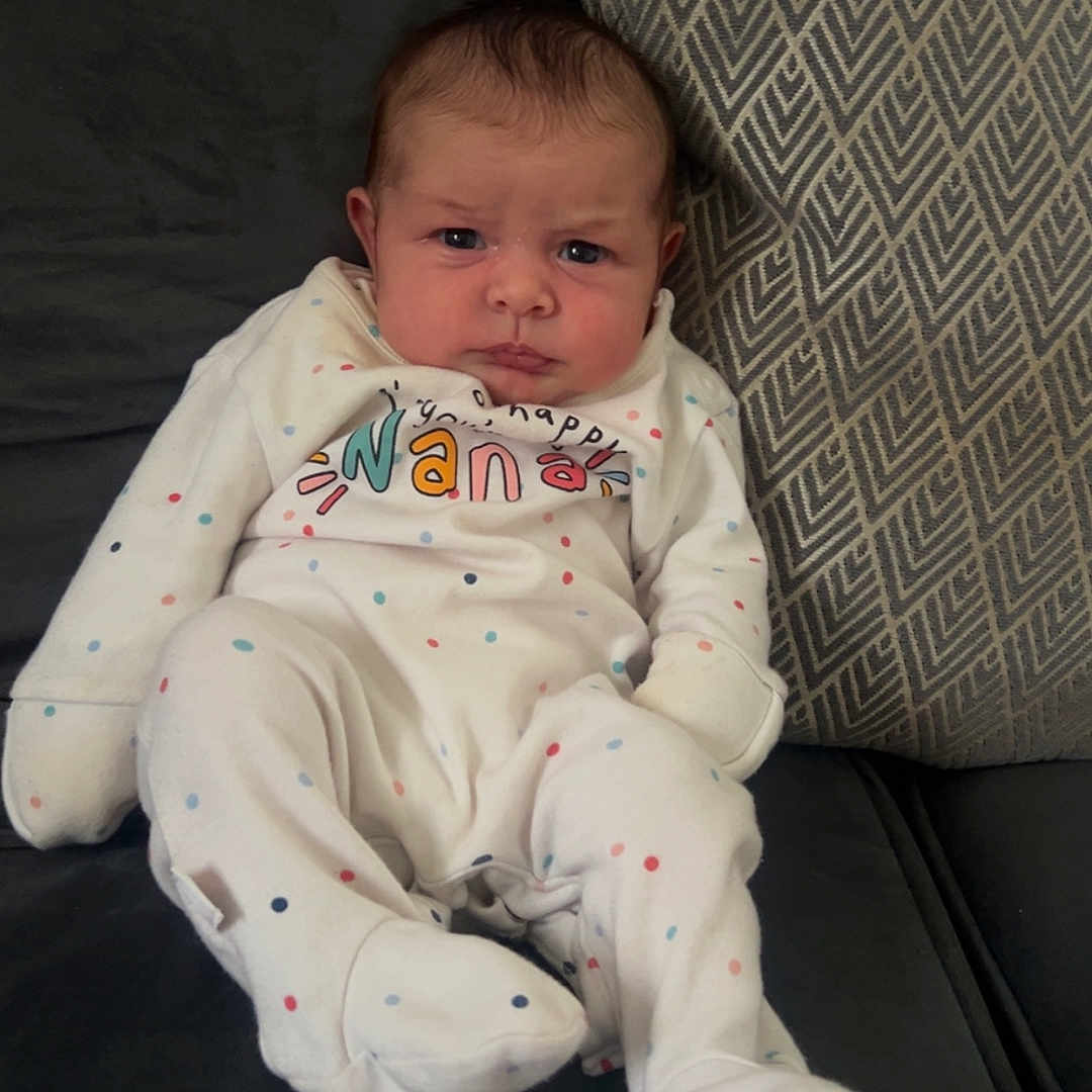 Maven-Louise joined the competition — help win amazing prizes! baby, child, clothing, couch, cute, expression, face, furniture, home, indoor, infant, onesie, patterned_pillow, person, pillow, polka_dots, portrait, relaxed, seated, young