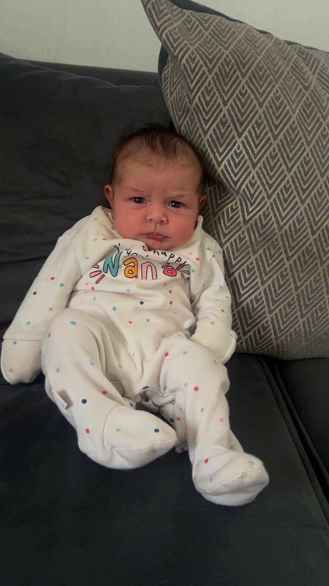 Maven-Louise joined the competition — help win amazing prizes! baby, infant, onesie, polka_dots, couch, pillow, patterned_pillow, indoor, seated, face, expression, person, child, young, clothing, home, furniture, cute, portrait, relaxed