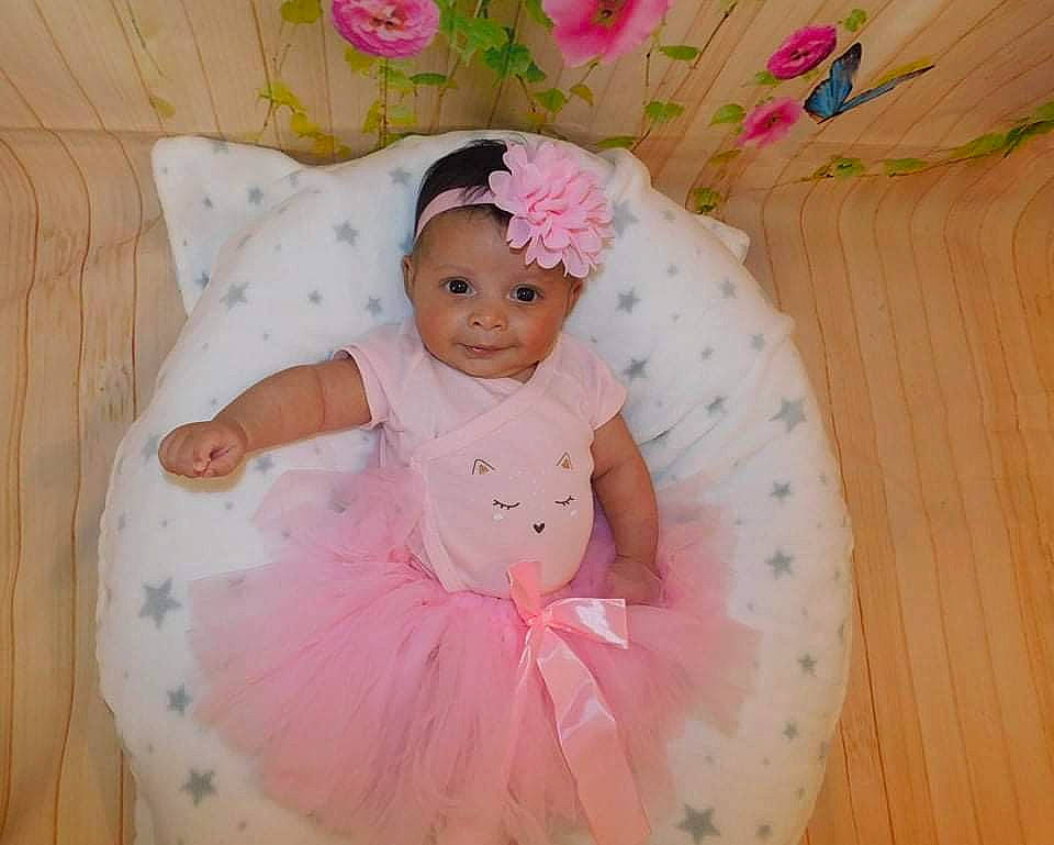 Louna a rejoint le concours — aidez-le/la à gagner de superbes lots ! baby, baby_products, baby_toddler_clothing, child, comfort, dress, face, facial_expression, fun, happy, headpiece, headwear, linens, magenta, pattern, person, pink, skin, sleeve, smile