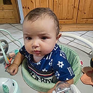 Natcho participe au concours pour gagner de l'argent avec cette photo : activity_center, baby, blue_shirt, child, closeup, curious, expression, face, floor_tiles, furniture, hand, home, indoor, infant, person, play, sitting, toy, wooden_cabinet, young_child