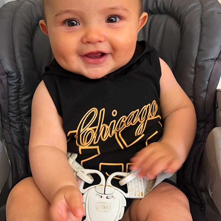 Natcho a rejoint le concours — aidez-le/la à gagner de superbes lots ! baby, black_shirt, child, chubby_arms, close_up, cute, face, happy, high_chair, indoor, infant, light_skin, person, playful, seat_belt, short_hair, sleeveless, smile, wooden_window, young_child