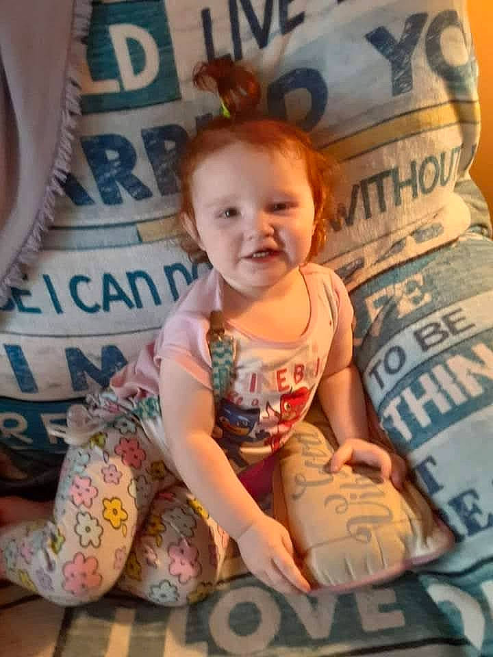 Lillian is registered to the contest to win money with this photo: arm, baby, baby_toddler_clothing, beauty, blond, cheek, child, facial_expression, hairstyle, happy, pattern, person, product, room, sitting, skin, sleeve, smile, t_shirt, textile