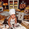baby, child, infant, chef_hat, bakery, baking, bread, pastry, pretzel, cookies, flour, messy, kitchen, food, sitting, portrait, costume, white_clothing, rolling_pin, birthday_photo