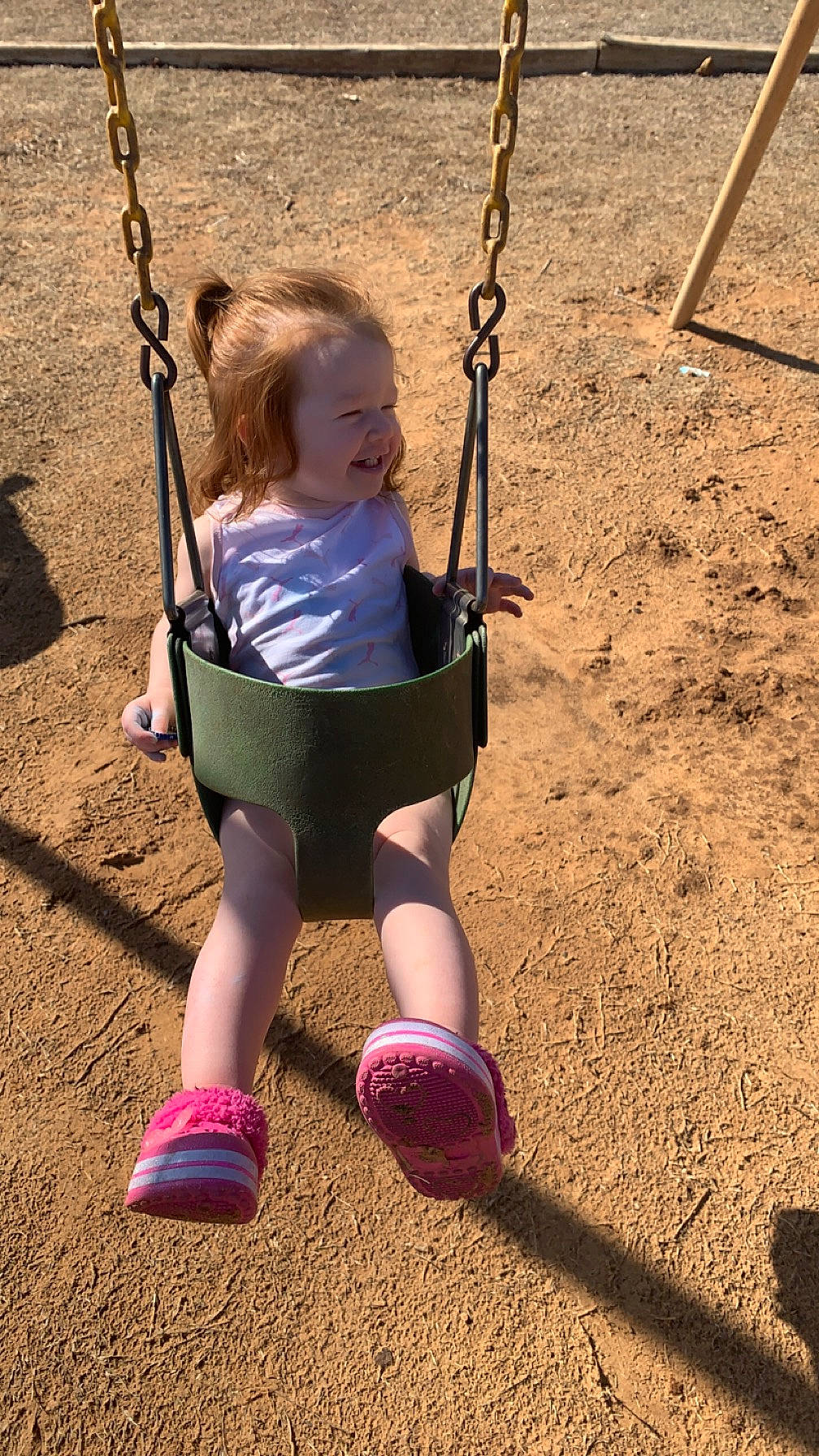 Mckenna is registered to the contest to win money with this photo: baby, black, child, city, fun, grass, happy, human_body, knee, leisure, outdoor_play_equipment, people_in_nature, person, play, playground, playing_sports, recreation, smile, swing, toddler