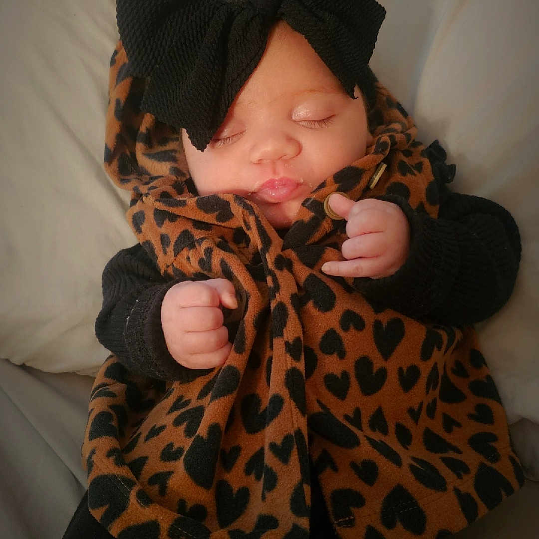 Opal is registered to the contest to win money with this photo: baby, bodypart, bonnet, cap, clothing, coat, couch, face, finger, furniture, hand, hat, head, hood, knitwear, newborn, person, photography, portrait, sweater