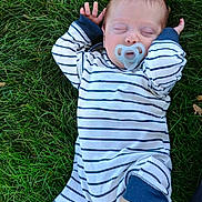 Sora is registered to the contest to win money with this photo: baby, infant, sleeping, pacifier, striped_clothing, grass, outdoor, nature, child, foot, hand, skin, relaxation, peaceful, one_piece, newborn, cute, lying_down, summer, soft_light