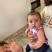 Truly is registered to the contest to win money with this photo: child, baby, toddler, indoor, person, floor, tile_floor, clothing, woman, hand, curly_hair, jeans, shirt, smile, playful, holding, sitting, heater, face, family