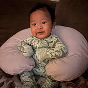 Keano John joined the competition — help win amazing prizes! baby, infant, pillow, leaf_pattern, onesie, couch, blanket, indoor, child, comfort, seated, soft_toys, cozy, smiling, cute, portrait, warm_lighting, home, furniture, young_child