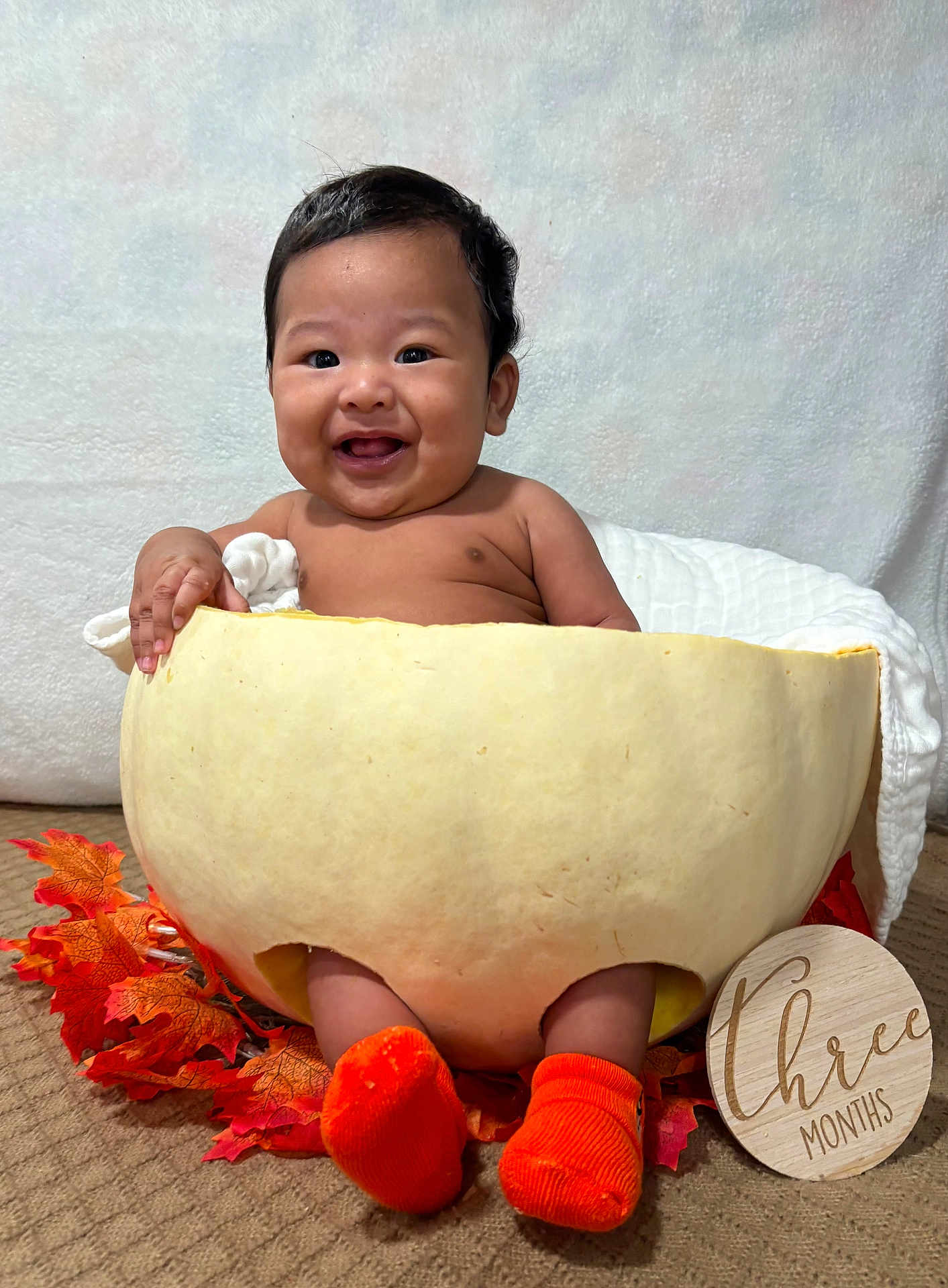 Keano John is registered to the contest to win money with this photo: baby, infant, pumpkin, orange_socks, autumn_leaves, carpet, wooden_sign, three_months, smiling, cute, milestone, cozy, indoor, celebration, fall, child, portrait, happy, seasonal, holiday
