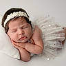 newborn, baby, sleeping, headband, white_dress, pillow, peaceful, portrait, infant, cute, resting, soft_lighting, studio_photo, child, toddler, closeup, face, hands, skin, adorable