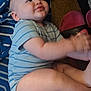 Logan is registered to the contest to win money with this photo: baby, child, infant, blue_onesie, striped_clothing, blanket, floor, slippers, red_slippers, hand_motion, candid, indoor, curious, content, plump, person, sitting, young_child, soft_skin, casual