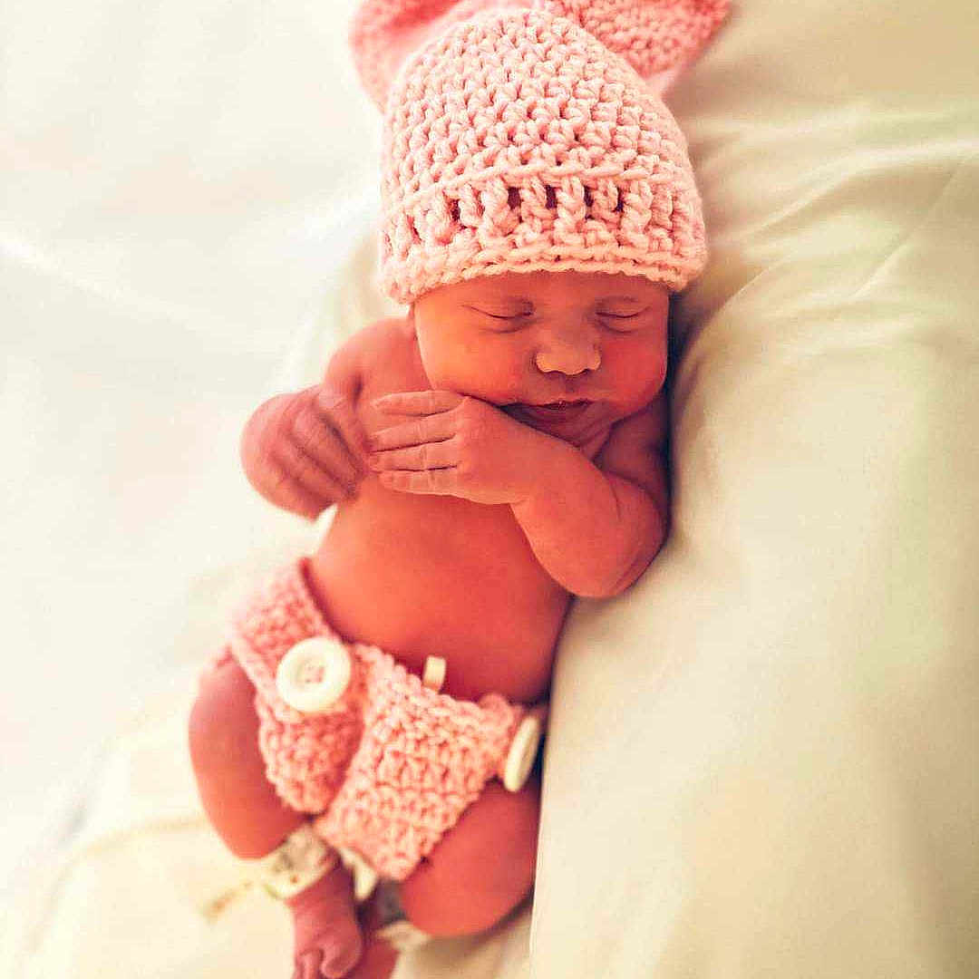 Everly is registered to the contest to win money with this photo: baby, beanie, bed, bedroom, blanket, bonnet, cap, clothing, face, furniture, glove, happy, hat, head, newborn, person, photography, portrait, sleeping, smile