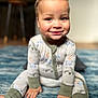 toddler, child, smile, pajamas, curly_hair, blue_eyes, indoor, rug, hands, feet, sitting, cute, cozy, face, person, infant, home, floor, happy, young_child