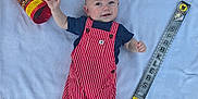 Revan is registered to the contest to win money with this photo: baby, infant, child, red_striped_overalls, blue_shirt, party_poppers, sparklers, blanket, smile, happy, celebration, colorful, footwearless, lying_down, cute, party, small_hands, soft_texture, indoors, playful