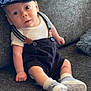 baby, child, sitting, couch, clothing, cap, suspenders, shoes, socks, indoor, furniture, portrait, cute, infant, face, looking, expression, home, soft, casual