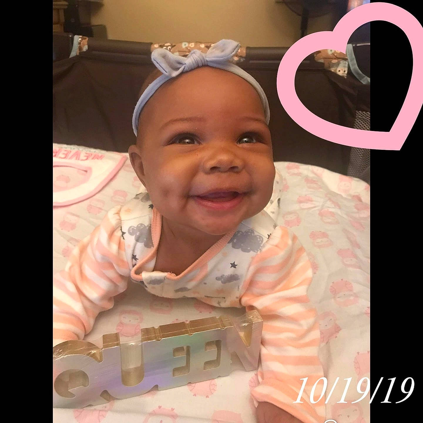 Queen is registered to the contest to win money with this photo: baby, cheek, child, cool, ear, eye, face, facial_expression, forehead, hair_accessory, happy, head, headband, joy, nose, person, photo_caption, photography, pink, skin