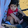 Juliett joined the competition — help win amazing prizes! baby, child, stroller, red_shirt, donut_pattern, blanket, curly_hair, outdoor, sunlight, infant, face, portrait, cute, seated, foot, hand, clothing, expression, baby_gear, soft_light