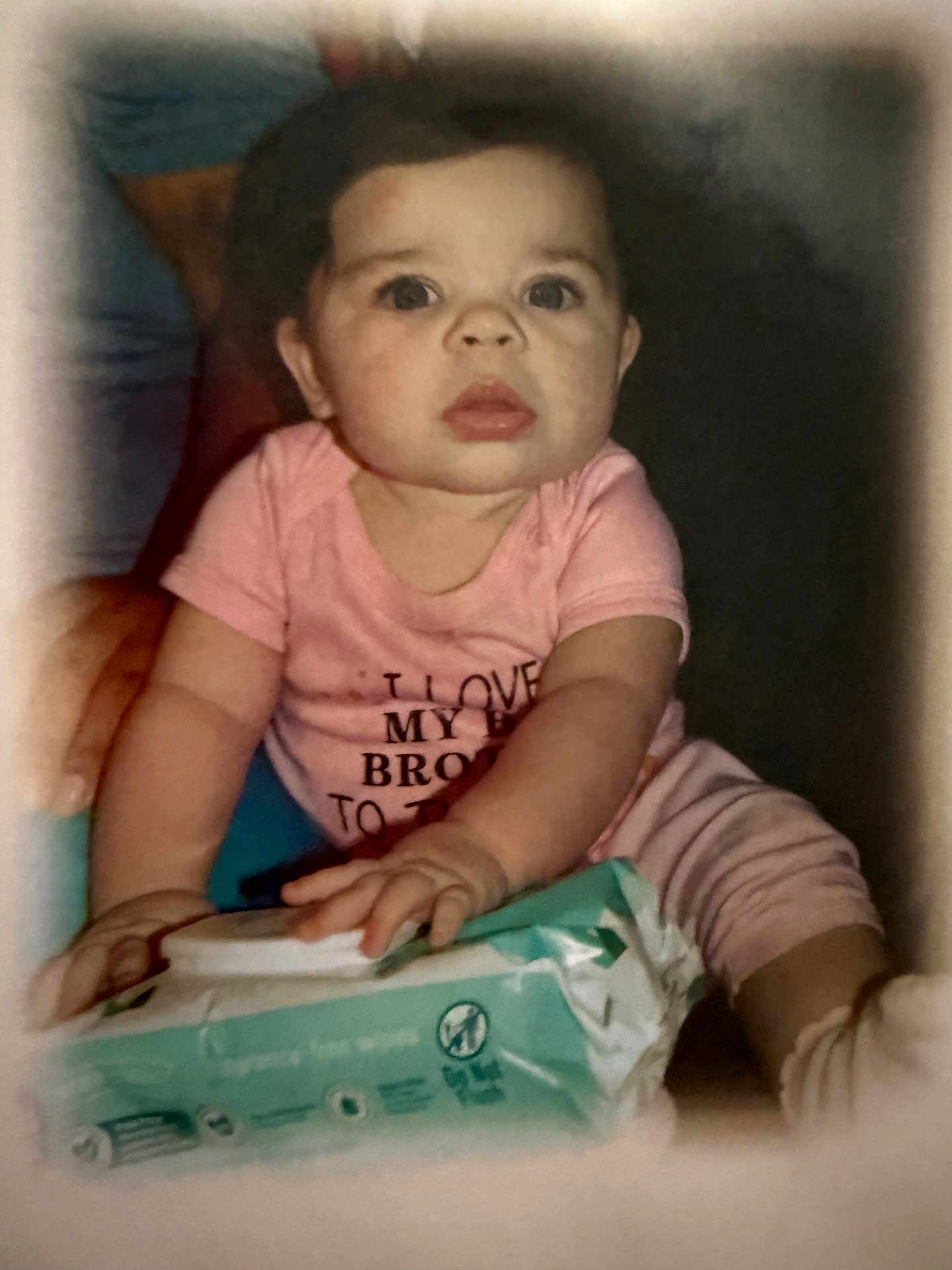 Lola is registered to the contest to win money with this photo: baby, infant, pink_clothing, face, hands, wipes, package, curious, indoor, portrait, child, young, crawling, closeup, expression, soft_light, vignette, sitting, person, focus