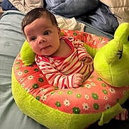 Lola joined the competition — help win amazing prizes! baby, infant, plush_toy, frog, striped_clothing, bed, blanket, pillow, face, person, cute, child, soft_toy, comfort, indoor, sleeping_area, rest, young_child, smile, lying_down