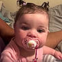 Lola joined the competition — help win amazing prizes! baby, pacifier, pink_clothing, indoor, pigtails, child, cute, face, person, infant, holding, soft_pillow, curious, closeup, young_child, human, head, skin, expression, seated