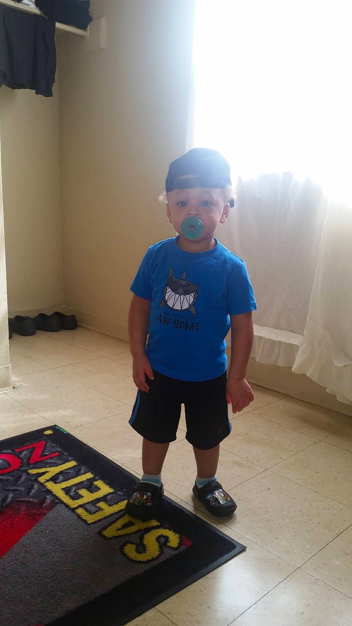 Jabari is registered to the contest to win money with this photo: arm, floor, flooring, headwear, joint, person, shoulder, standing, t_shirt