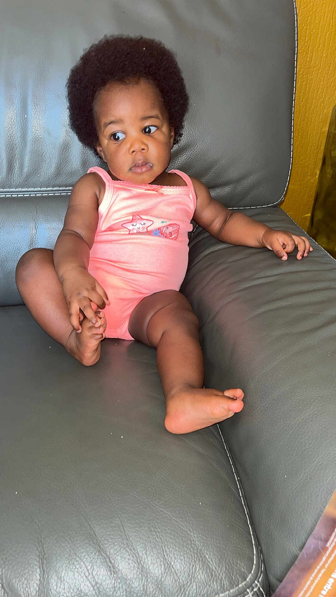 Majalys participe au concours pour gagner de l'argent avec cette photo : toddler, baby, afro, pink_onesie, couch, leather, child, indoor, skin, foot, hand, curious, sitting, comfortable, expression, young_child, casual, relaxed, furniture, home
