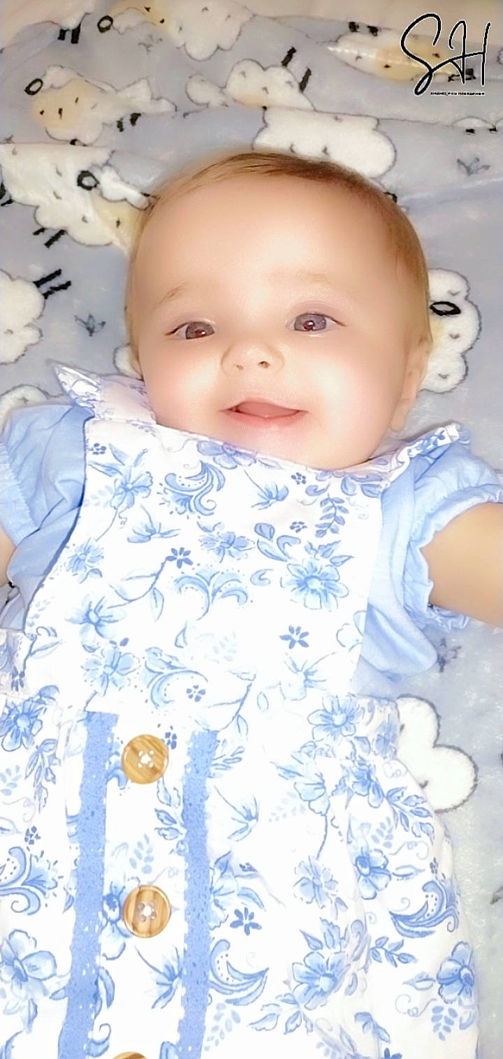 Rosie-maria is registered to the contest to win money with this photo: azure, baby, baby_toddler_clothing, cheek, chin, dress, eyebrow, eyelash, face, happy, iris, lip, mouth, neck, nose, person, photograph, skin, sleeve, smile