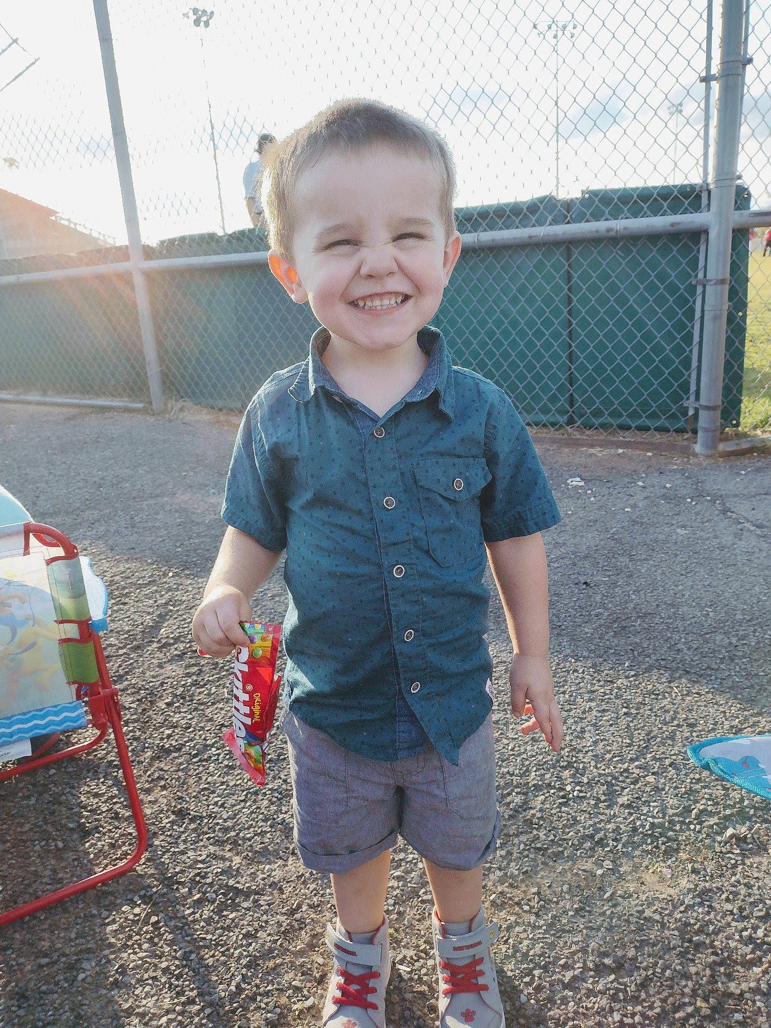 Cody Robert is registered to the contest to win money with this photo: baby_toddler_clothing, denim, electric_blue, face, fence, fun, grass, happy, head, human_body, joy, leg, leisure, outerwear, person, shorts, sleeve, smile, standing, summer
