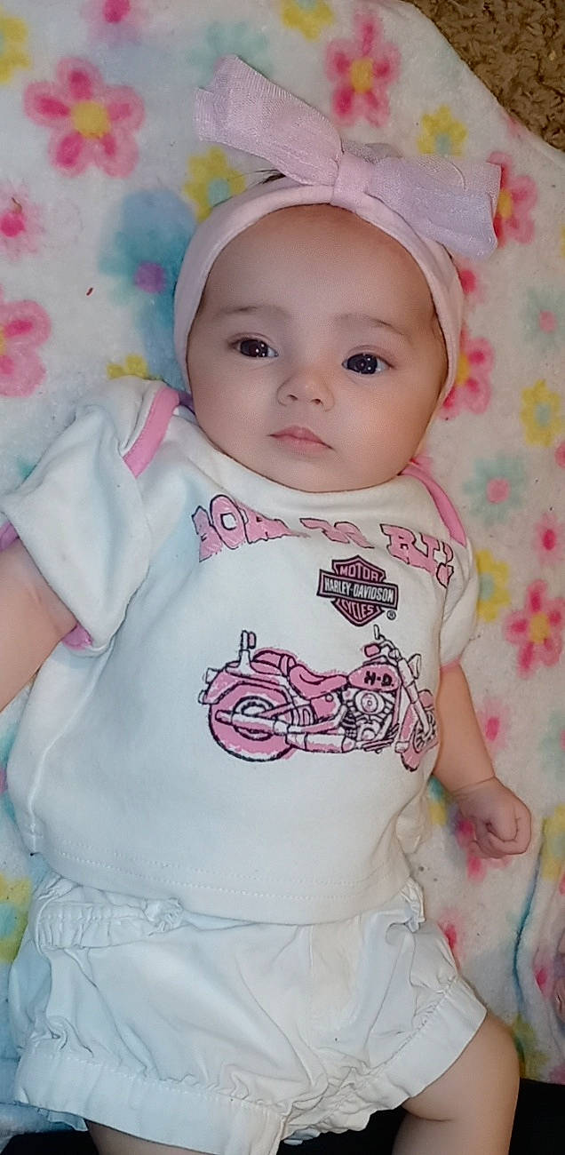 Rosie-maria is registered to the contest to win money with this photo: baby, baby_toddler_clothing, cheek, child, collar, dress, happy, headgear, headwear, iris, lip, magenta, nose, outerwear, pattern, person, pink, skin, sleeve, t_shirt