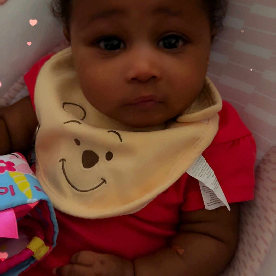 Akira is registered to the contest to win money with this photo: baby, infant, child, bib, red_clothing, smiling_bear, cushion, seat, hand, face, curly_hair, heart_overlay, soft_toy, blanket, indoor, portrait, cute, adorable, expression, closeup