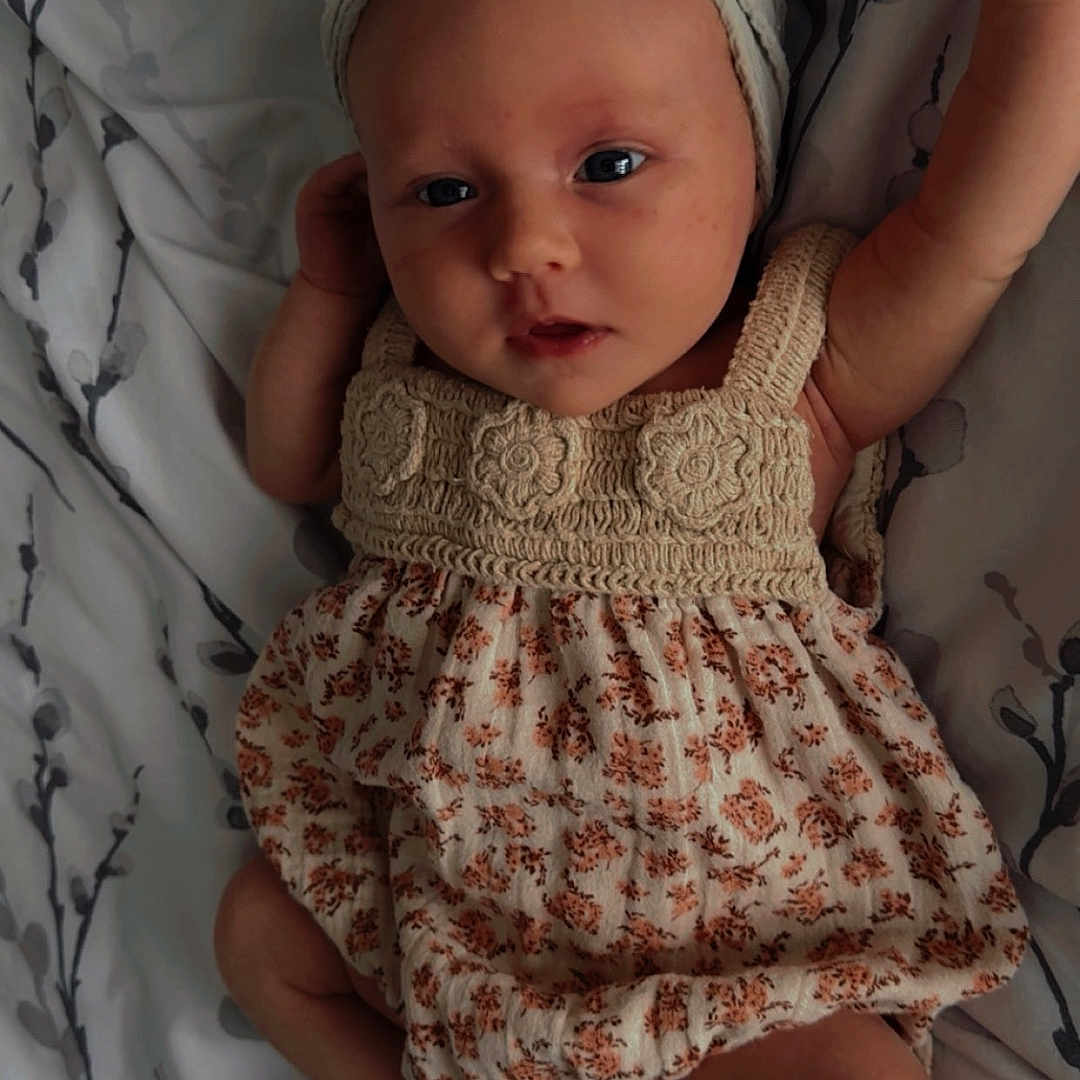 Maddie-Rose joined the competition — help win amazing prizes! adorable, baby, bedspread, bow, child, cute, dress, eyes, fabric, face, floral_pattern, foot, hand_up, headband, indoors, infant, lying_down, portrait, skin, soft_lighting