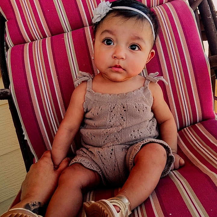 Aleyda is registered to the contest to win money with this photo: baby, bodypart, chair, clothing, couch, cushion, face, finger, footwear, furniture, hand, hat, head, homedecor, pants, person, photography, portrait, shoe, sitting