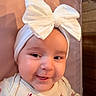 Everly is registered to the contest to win money with this photo: baby, child, infant, headband, bow, smile, cheeks, clothing, pink, cushion, face, portrait, cute, young, indoors, apparel, person, closeup, happy, fashion