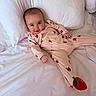 baby, child, infant, pajamas, strawberry_pattern, bed, white_bedspread, pillow, smile, cute, lying_down, happy, indoors, person, sleepwear, soft, comfortable, cozy, young, relaxed