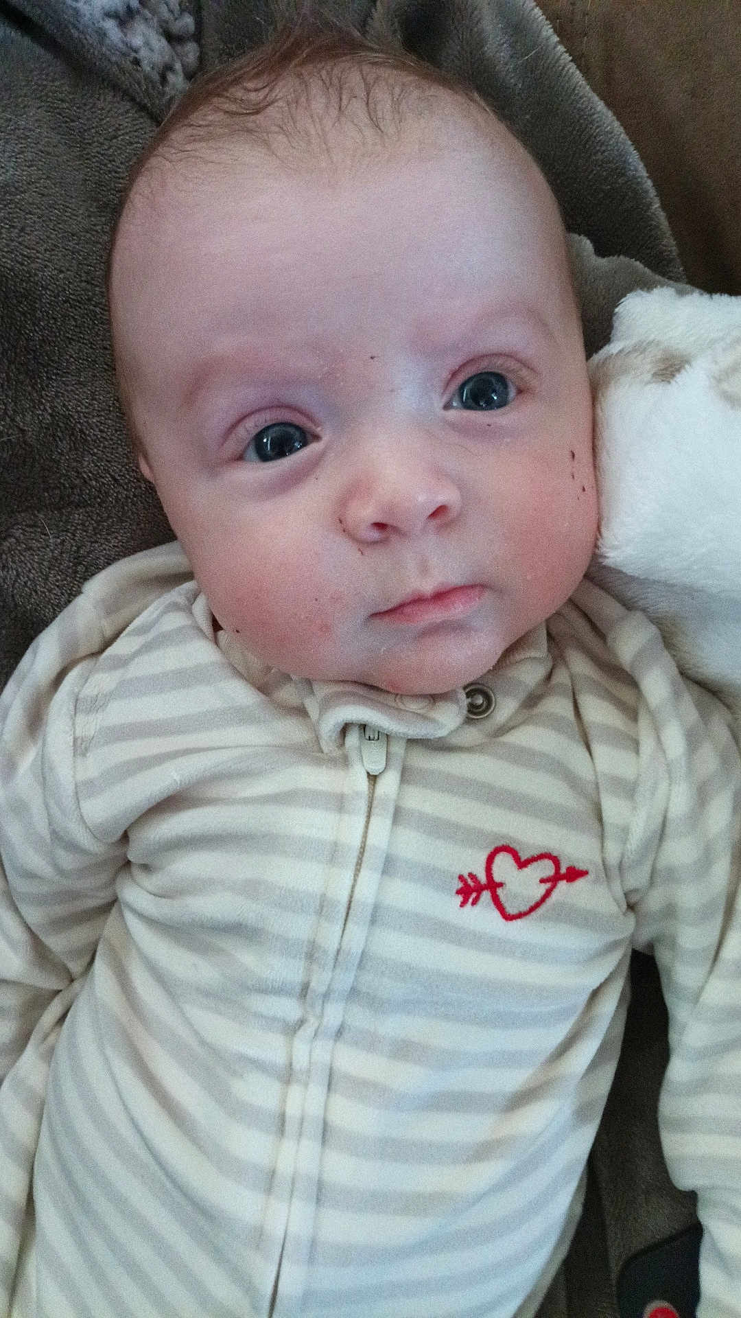 Kasen joined the competition — help win amazing prizes! baby, infant, newborn, onesie, striped_clothing, heart_logo, blanket, couch, closeup, face, eyes, cheeks, skin, hair, zipper, portrait, lying_down, cozy, soft_texture, expression
