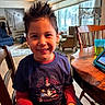 Nathan is registered to the contest to win money with this photo: child, boy, smiling, spiky_hair, sitting, table, wooden_chair, living_room, window, couch, staircase, sippy_cup, tablet, indoor, casual_clothing, happy, home, person, daylight, portrait