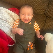 Justin joined the competition — help win amazing prizes! baby, blanket, child, couch, cozy, face, hands, happy, home, indoor, infant, laughing, legs, overalls, portrait, sitting, smiling, striped_shirt, tiger_patch, toy