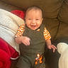 baby, blanket, child, couch, cozy, face, hands, happy, home, indoor, infant, laughing, legs, overalls, portrait, sitting, smiling, striped_shirt, tiger_patch, toy