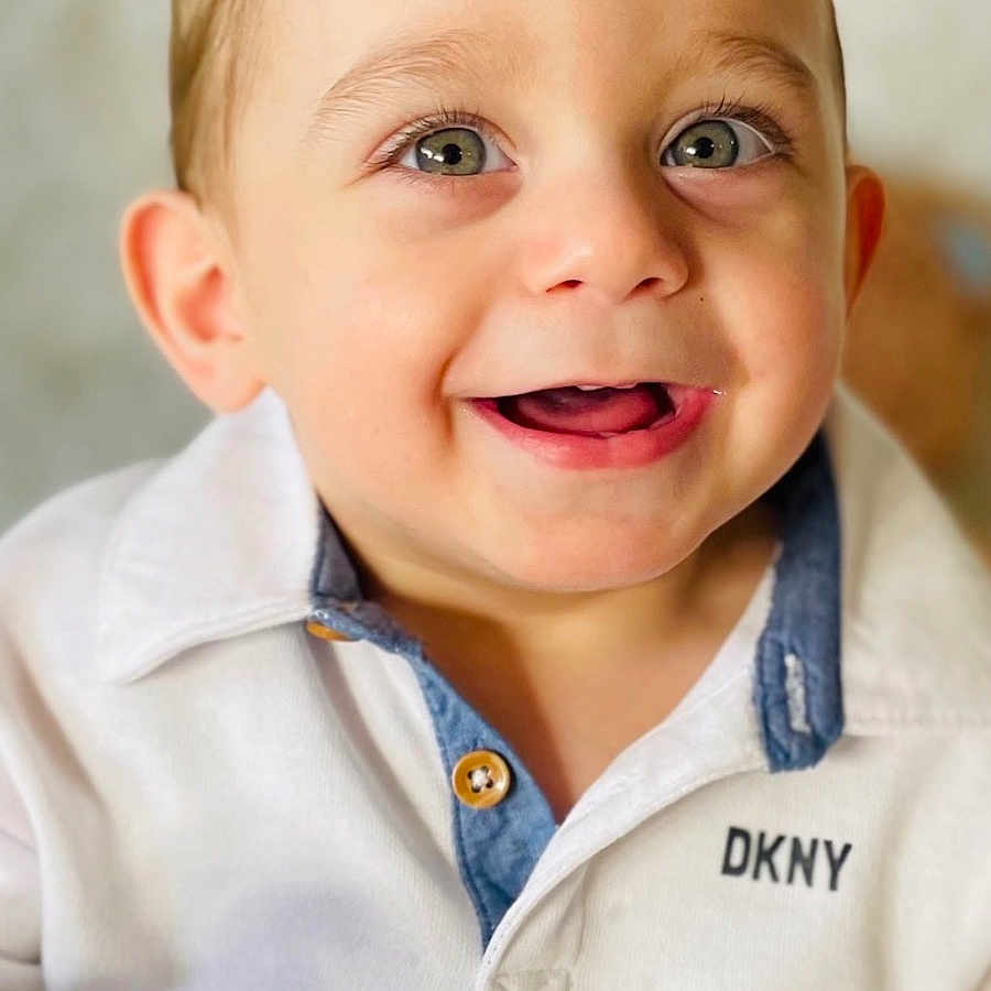 Neymar Najm is registered to the contest to win money with this photo: child, toddler, smiling, face, eyes, white_shirt, clothing, portrait, happy, cute, indoor, person, baby, young_child, closeup, fashion, casual, light, skin, head