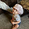 Ensley is registered to the contest to win money with this photo: toddler, child, indoors, carpet, toy, shower_cap, pink, heart_pattern, gray_shirt, denim_shorts, smiling, sitting, living_room, couch, table, carpeted_floor, person, casual_clothing, happy, home
