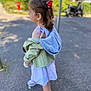 casual_clothing, child, curly_hair, daytime, dress, girl, hairclip, jacket, nature, outdoor, pavement, person, red_flower, shadow, side_profile, sneakers, sunlight, urban, walking, young