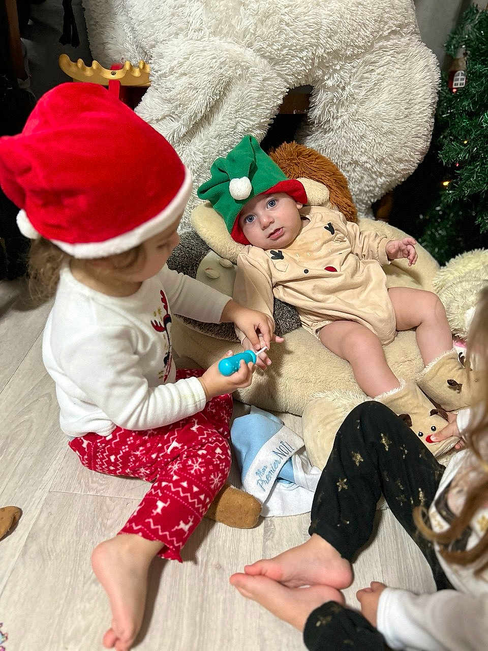 Rita a rejoint le concours — aidez-le/la à gagner de superbes lots ! baby, toddler, child, christmas, holiday, elf_hat, santa_hat, plush_chair, toy, pajamas, floor, playing, indoor, festive, boots, cute, family, fun, happy, cozy