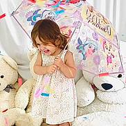 Rita a rejoint le concours — aidez-le/la à gagner de superbes lots ! celebration, child, childhood, colorful, confetti, cute, dress, floor, fun, girl, happy, indoors, person, playful, portrait, sandals, smiling, teddy_bear, toy, umbrella