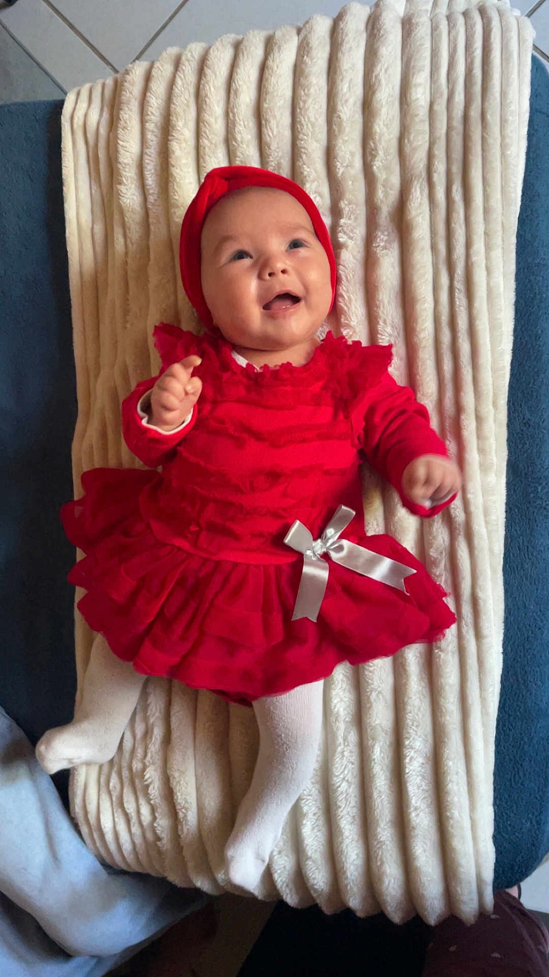 Mia participe au concours pour gagner de l'argent avec cette photo : baby, child, red_dress, headband, blanket, smile, happy, toddler, white_tights, infant, cute, lying_down, indoor, soft_texture, ribbon, playful, young_child, portrait, cozy, adorable
